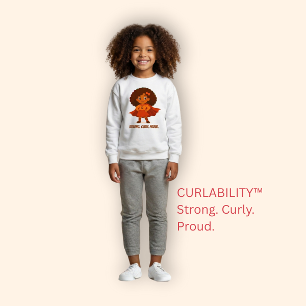 Studio portrait of a child model wearing a white “Strong. Curly. Proud.” curly-hair graphic sweatshirt — kids’ empowerment clothing by Curlability.