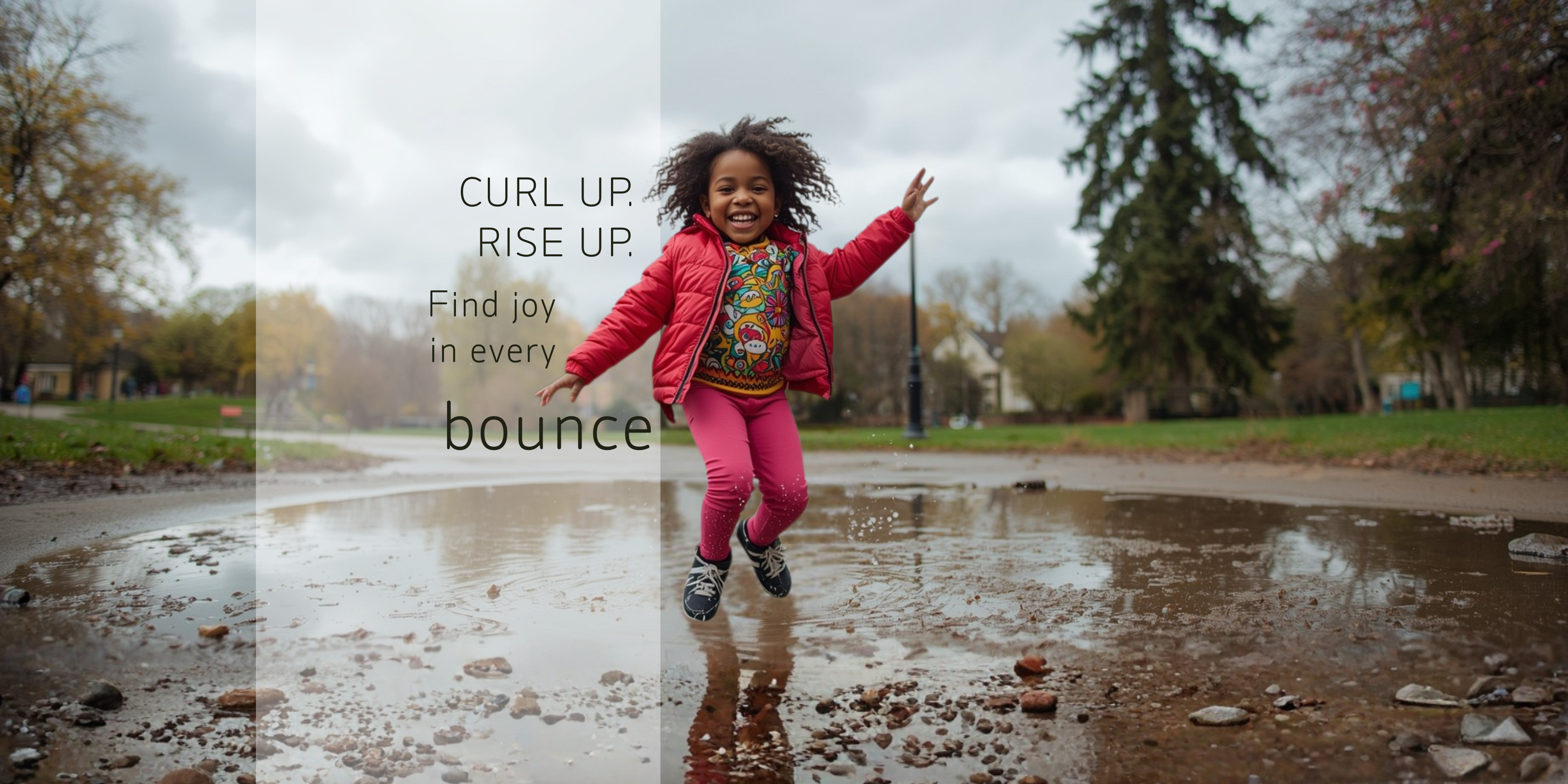 Curly-haired girl jumping in a puddle on a cloudy day at the park.